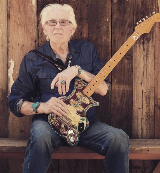 an older man sitting on a bench holding a guitar