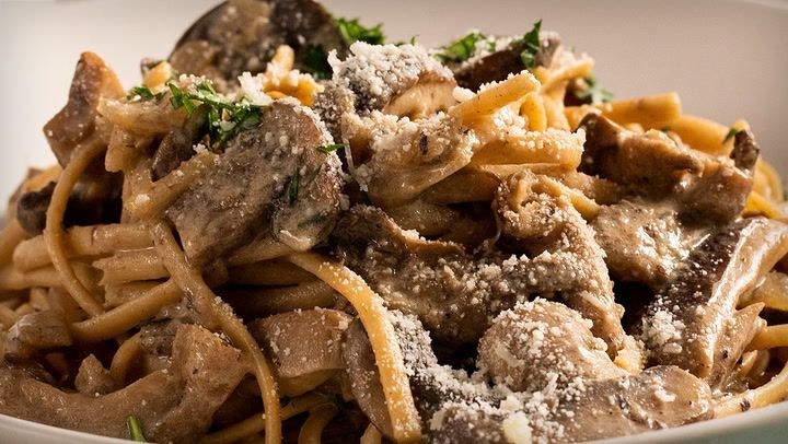 pasta with meat and parmesan cheese in a white bowl on top of a table