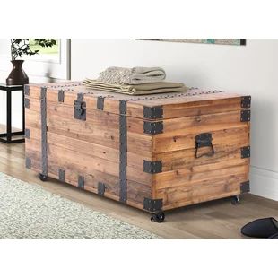 a large wooden trunk sitting on top of a hard wood floor next to a rug