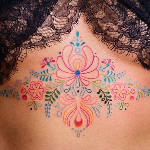 a woman's back with colorful tattoos on it