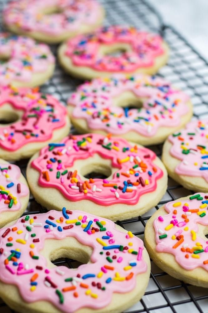 there are many donuts with pink frosting and sprinkles on the cooling rack