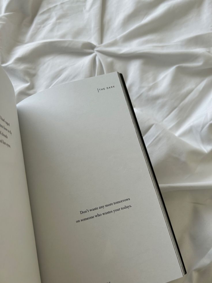 an open book sitting on top of a bed next to a white sheet covered floor