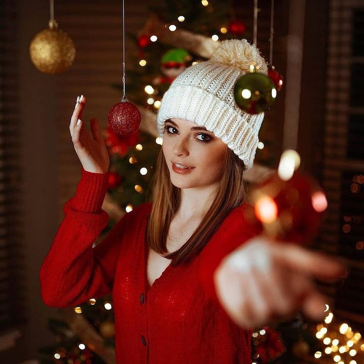 a woman wearing a white knitted hat and holding two ornaments