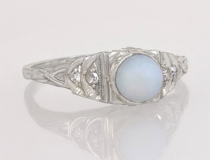 an art deco ring with a blue stone in the center and diamond accents on each side