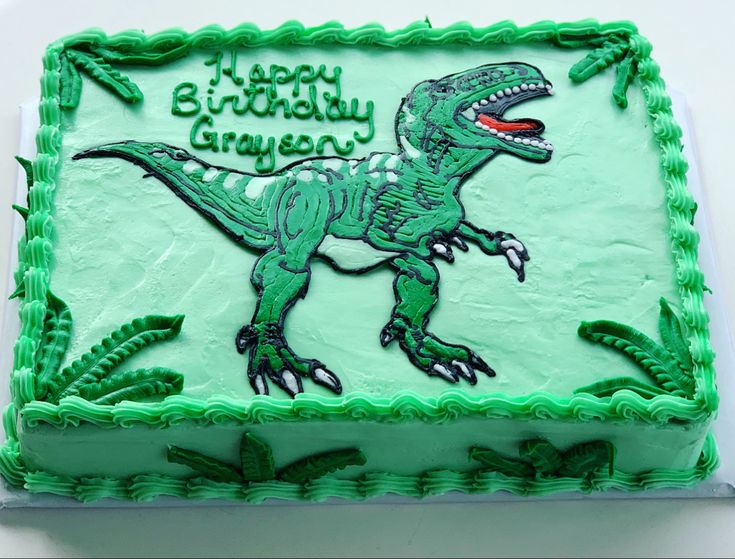 a green birthday cake with a dinosaur on it