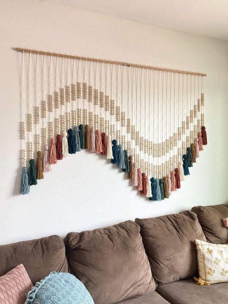 a living room with a brown couch and some tassels hanging on the wall