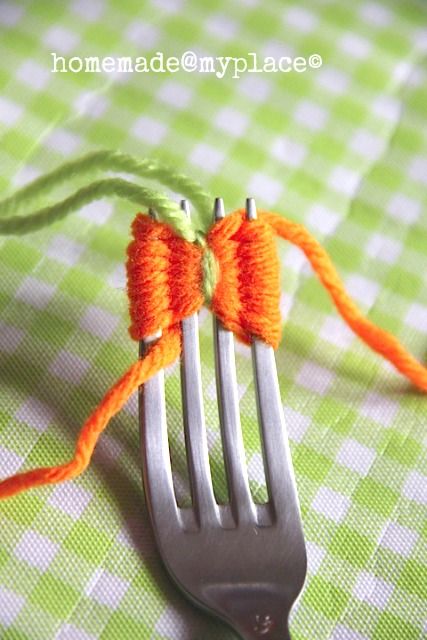 a fork with two orange bows on it sitting on a green and white checkered table cloth