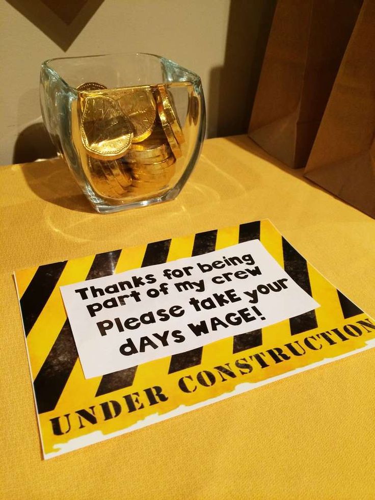 there is a sign that says under construction next to a glass bowl with gold coins in it