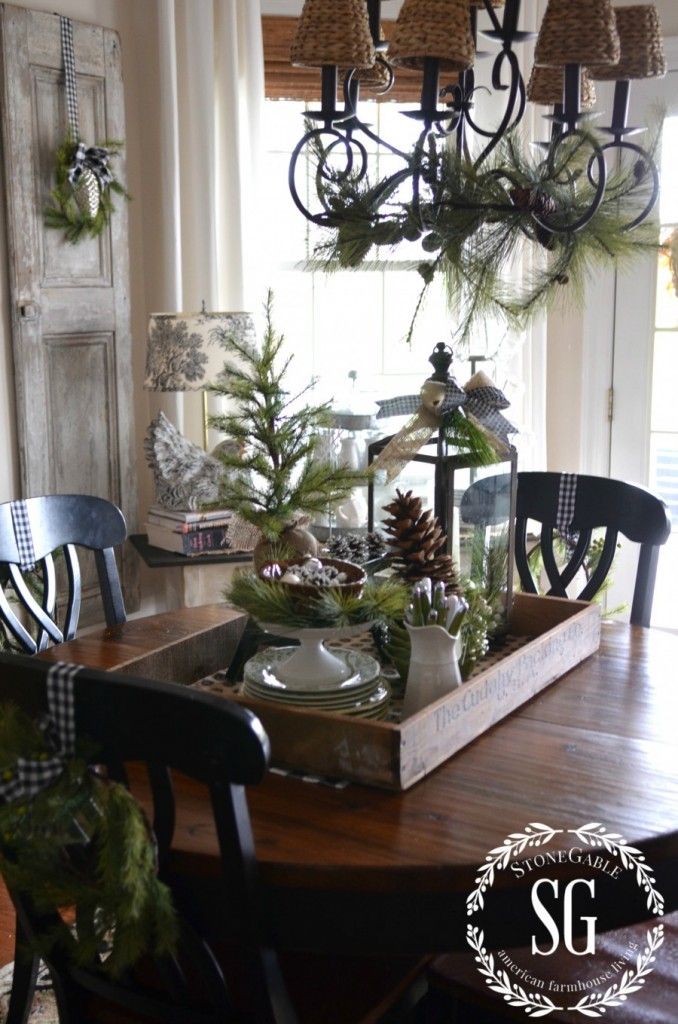 a dining room table decorated for christmas with pine cones and greenery on the top