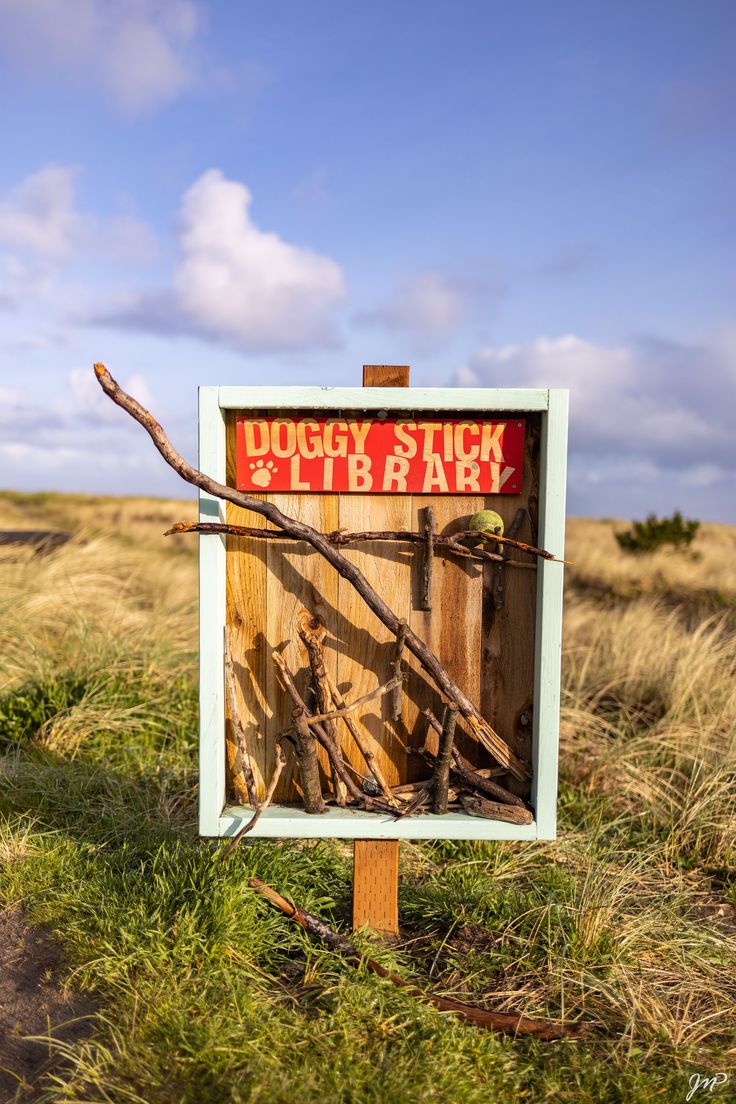 a sign that is in the grass with some sticks sticking out of it's back