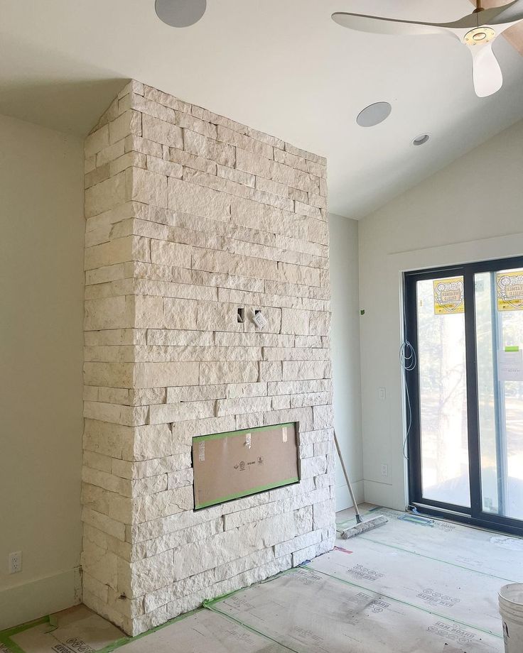 an empty room with a brick fireplace in the middle and doors to another room behind it