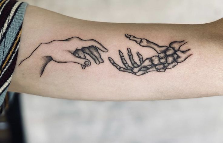 two hands reaching out to each other with the creation behind them tattoo design on arm