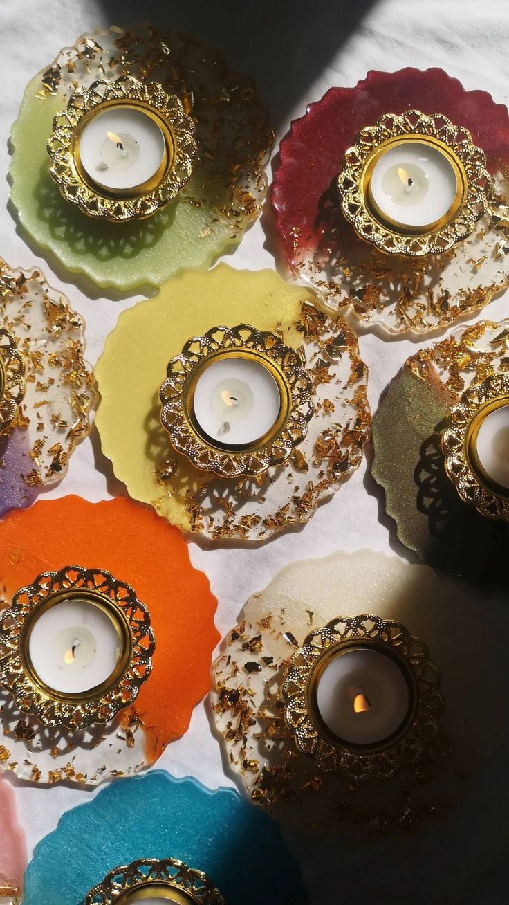 many different colored candles sitting on top of each other in front of a white table cloth