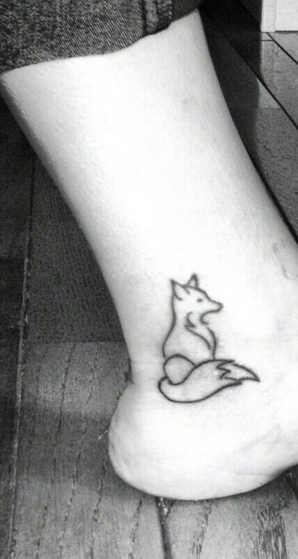 a black and white photo of a person's foot with a small fox tattoo on it