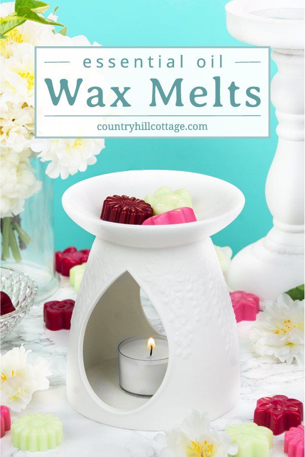 a white wax melter sitting on top of a table next to flowers and candles