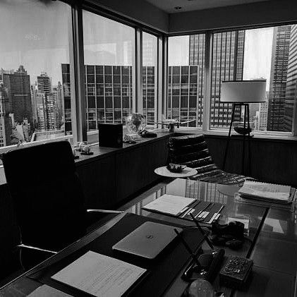 an office with large windows and desks in front of the cityscape is shown