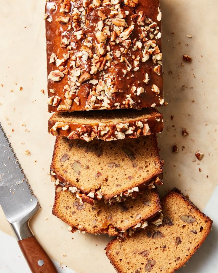 sliced loaf of banana nut bread on top of a cutting board with a knife next to it