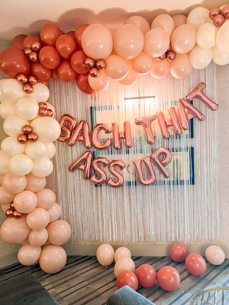 balloons and streamers decorate the entrance to a party with an arch that reads, bacthing aster