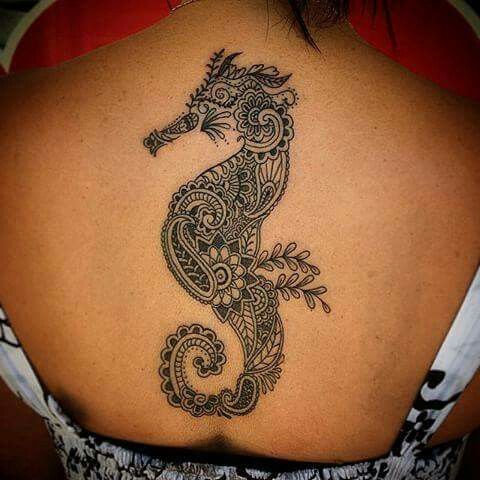 the back of a woman's shoulder with a sea horse tattoo design on it