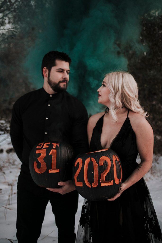 a man and woman standing next to each other holding pumpkins