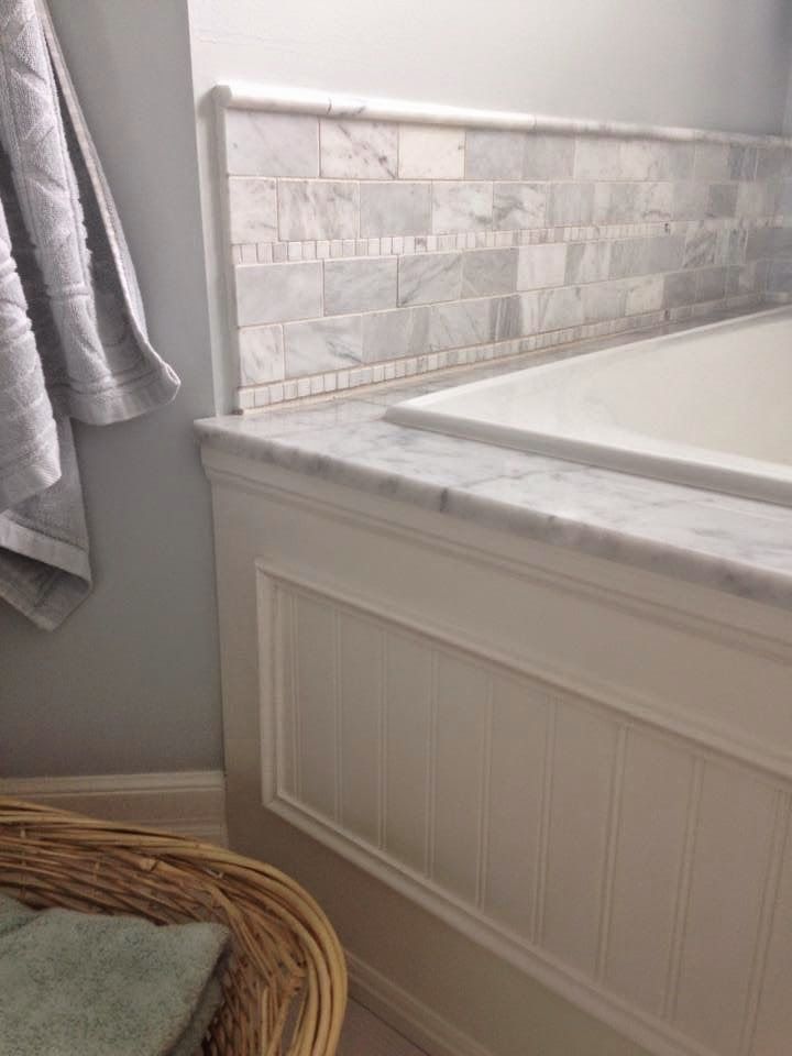 a white bath tub sitting under a window next to a towel rack with towels on it