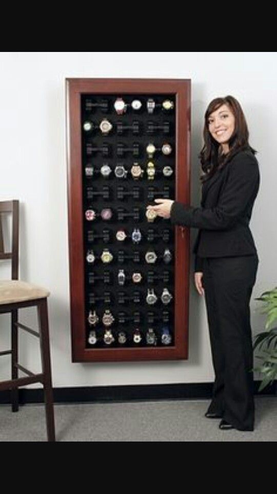 a woman standing next to a wall mounted watch display