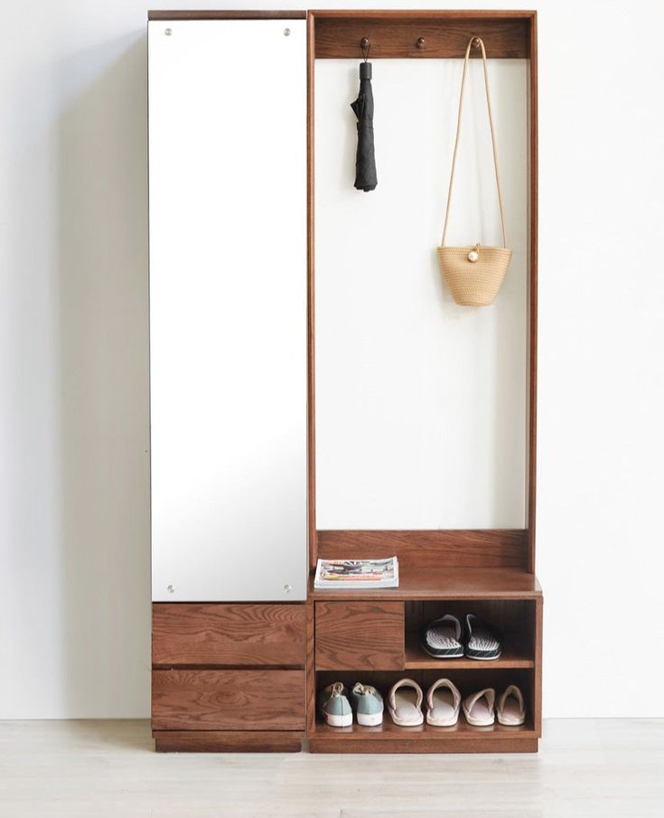 a wooden shoe cabinet with mirror and shoes on the bottom shelf in front of it