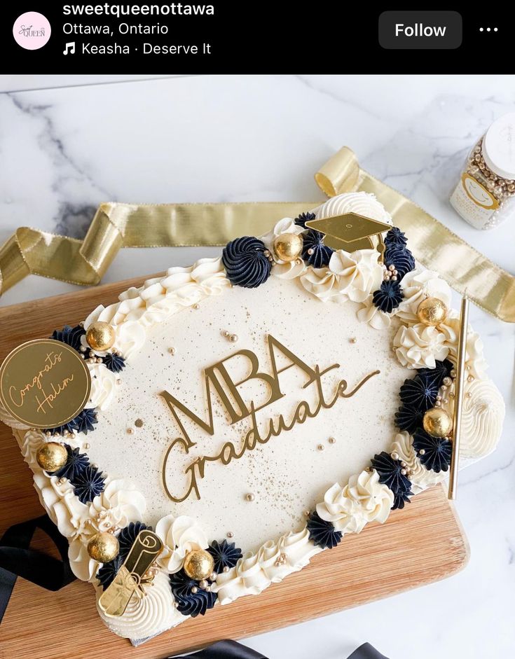 a white cake with gold lettering on it sitting on top of a wooden cutting board