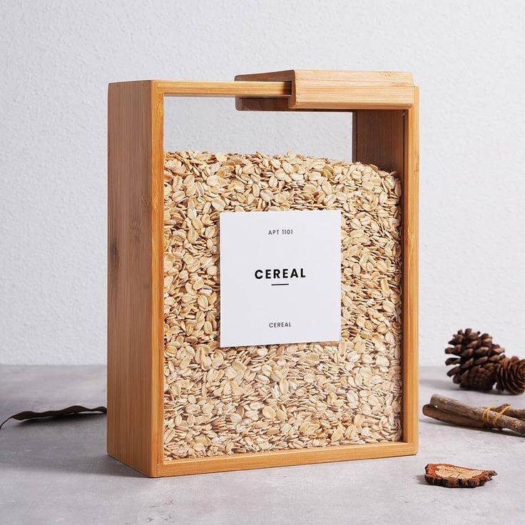 a wooden box filled with oats next to a pine cone