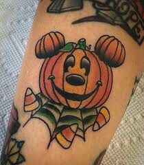 a person with a mickey mouse tattoo on their arm and leg, holding a pumpkin