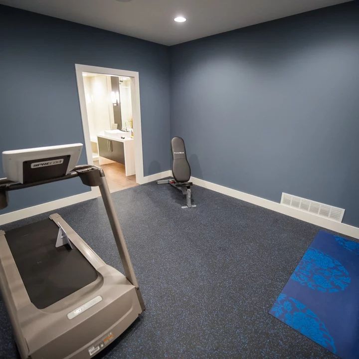 an exercise room with treadmills and blue carpeted flooring is pictured in this image