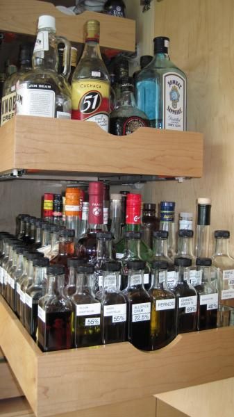 the shelves are filled with liquor bottles and other condiments, including alcohol glasses