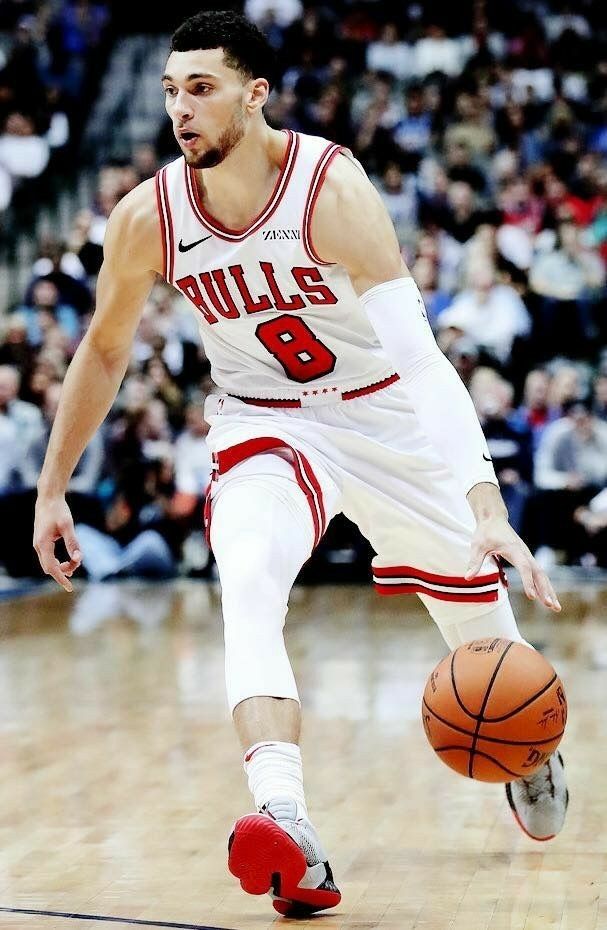 a basketball player dribbling the ball during a game in front of an audience