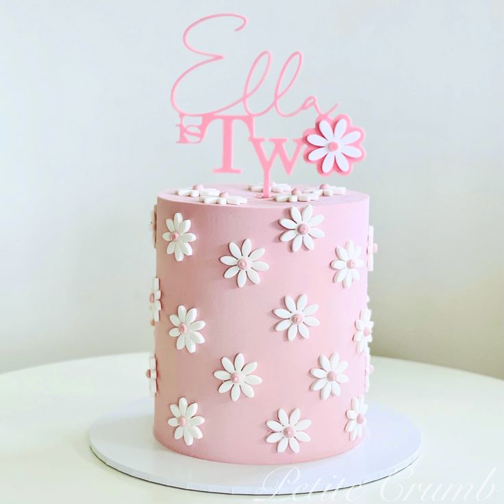 a pink and white cake with flowers on it that says ell't two