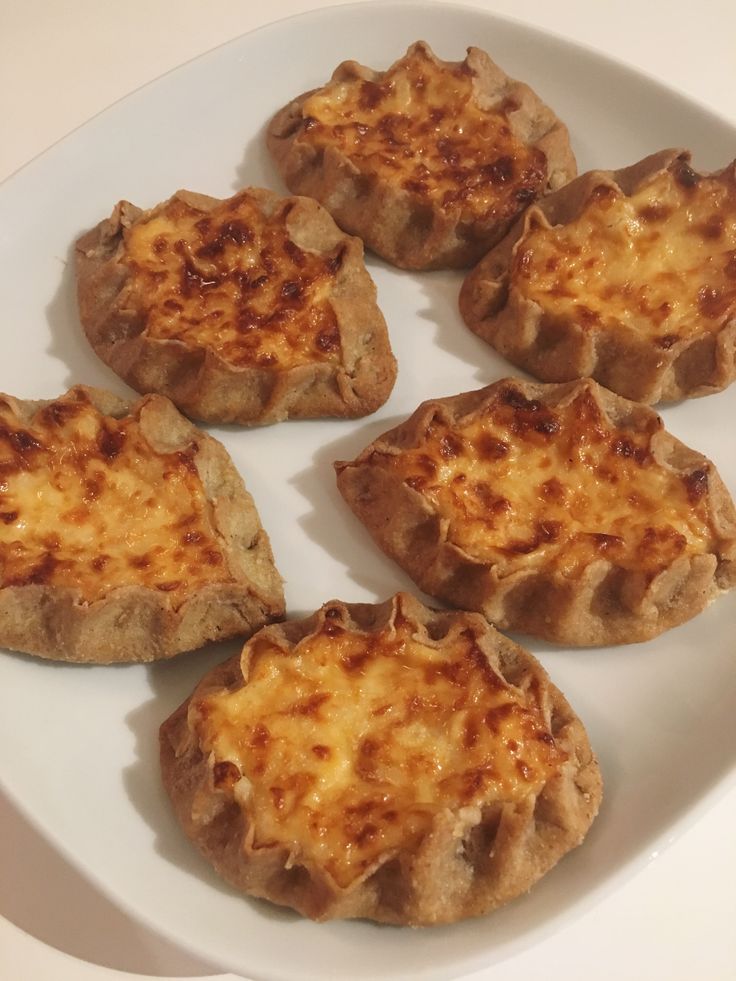 four pieces of pizza on a white plate with cheese toppings in the shape of hearts