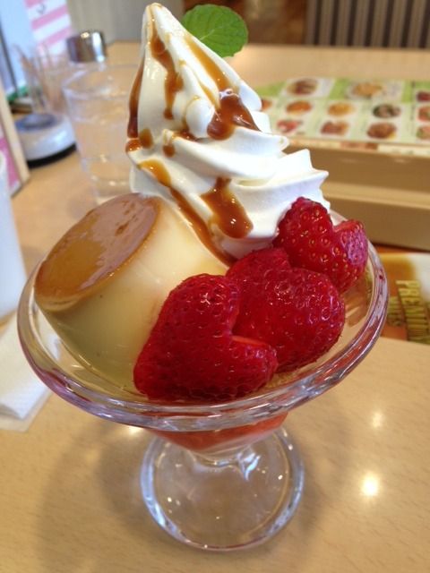 an ice cream sundae topped with raspberries and caramel sauce on a table