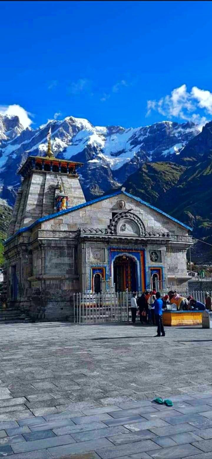 people are standing in front of a small building with mountains in the backgroud