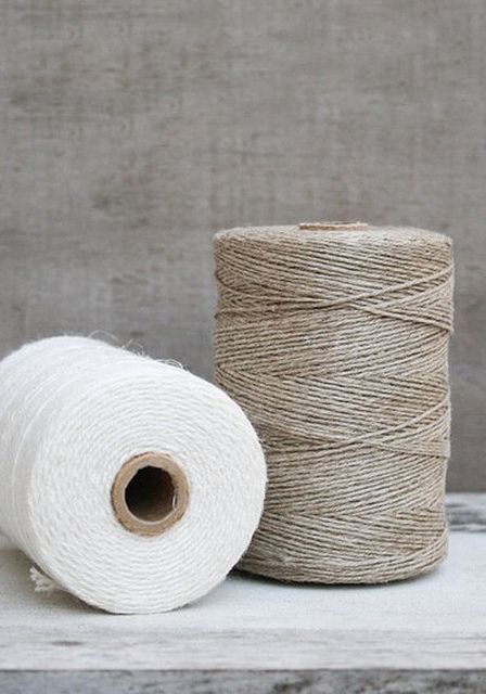 two spools of twine next to each other on a wooden surface with white yarn