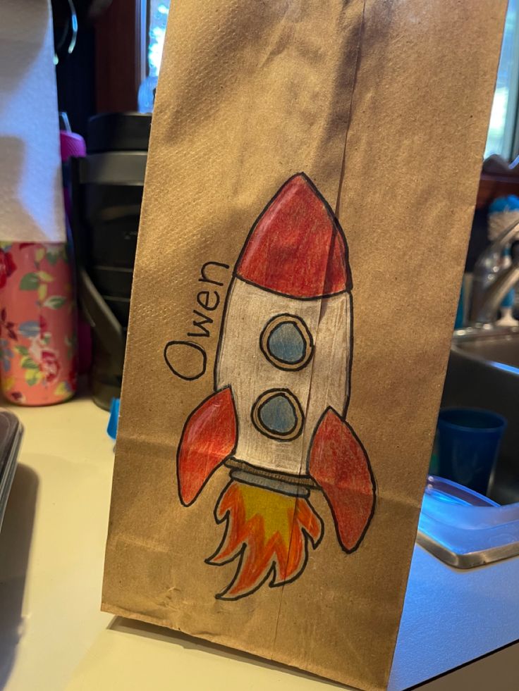 a brown paper bag with a drawing of a rocket ship on it's side