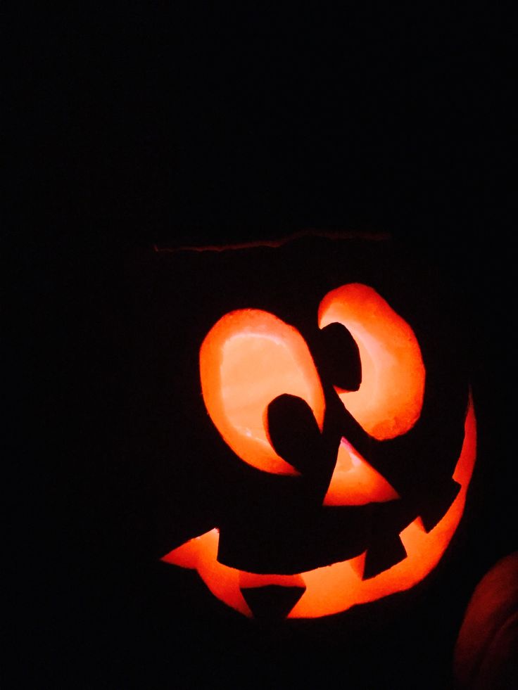 a carved pumpkin with the letter g on it's face, in the dark