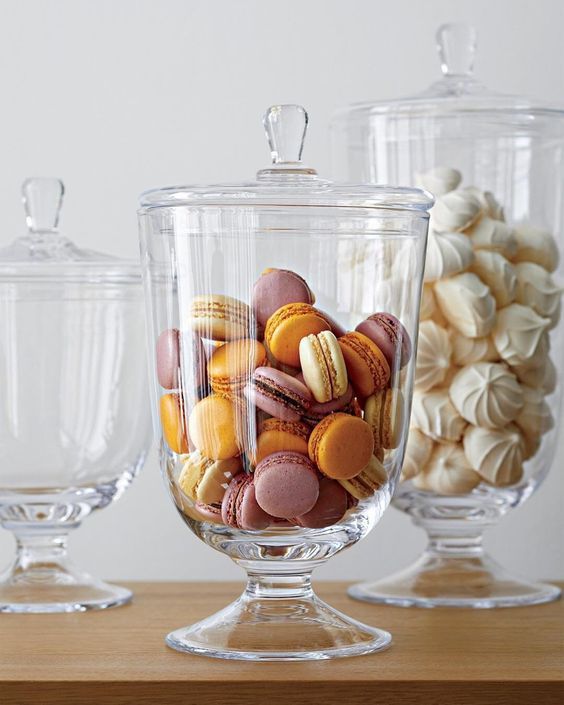 three glass containers filled with different types of candies on top of a wooden table