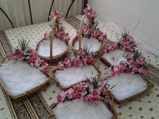 several baskets with flowers in them sitting on a table next to a wall and rug