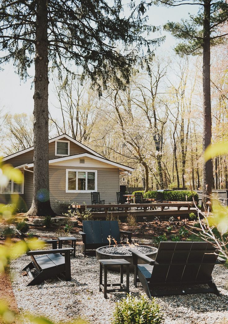 there is a small house in the woods with many chairs around it and a fire pit