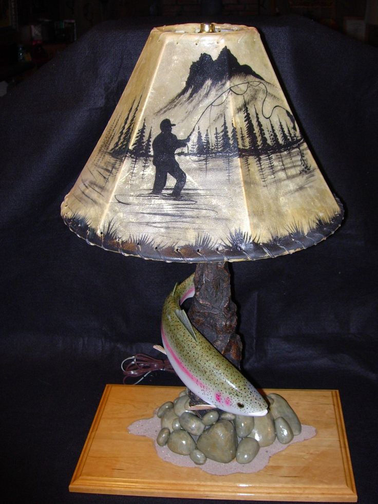 a lamp that has a fish on it and a man fishing in the water underneath