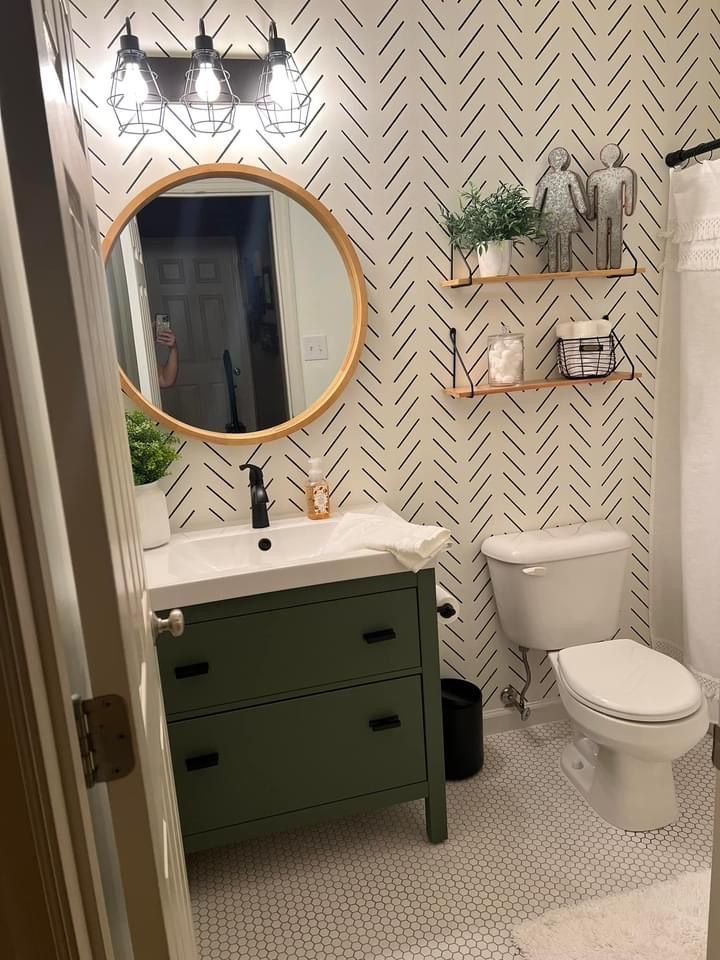 a white toilet sitting next to a sink in a bathroom under a mirror and shelves