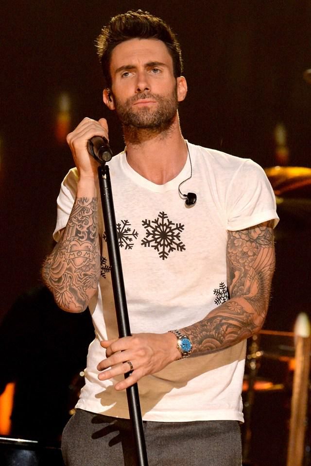 a man with tattoos on his arm holding a microphone and standing in front of a stage