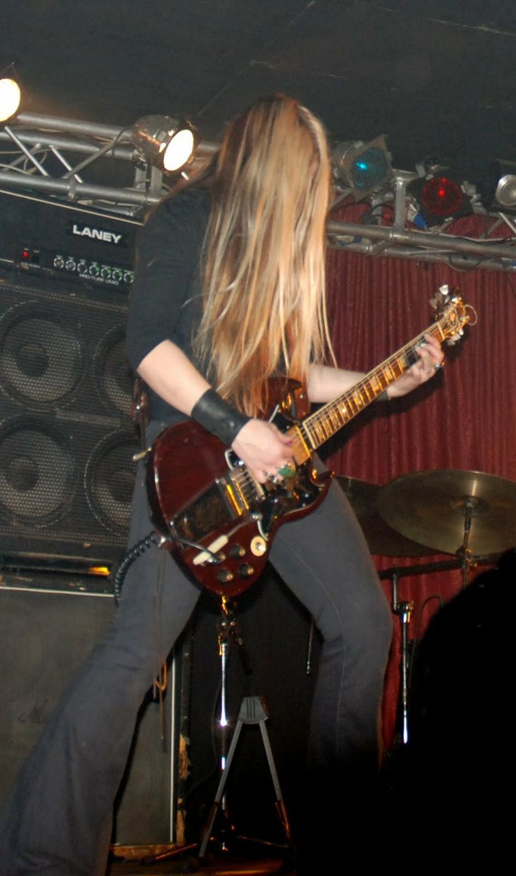 a woman with long hair playing an electric guitar