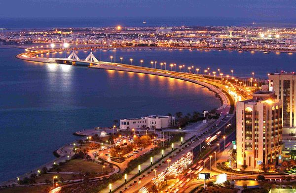 an aerial view of a city at night with lights on the buildings and water in the background