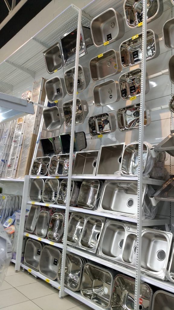 the shelves are full of silver dishes and pans on display in a kitchen store