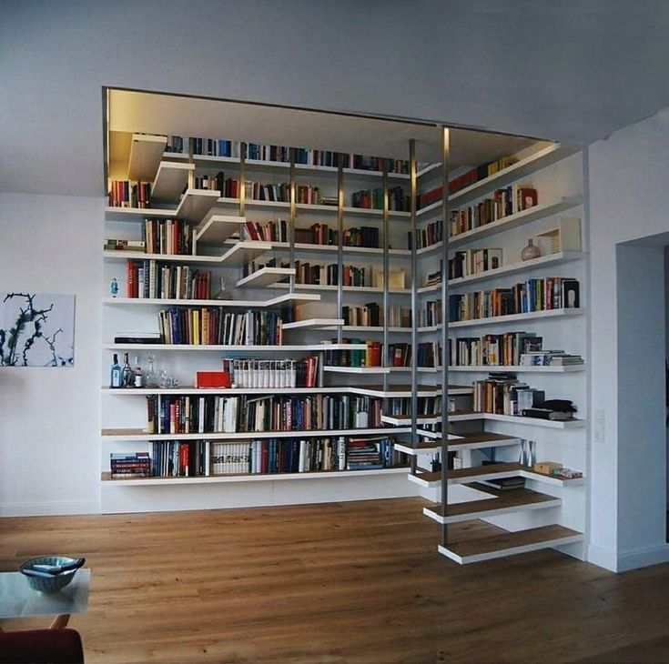 a living room filled with lots of books on shelves next to a stair case full of books